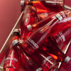 Red bottles with 'Clubmed' branding on a metallic tray against a red background