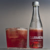 A bottle of CLUBMERA sitting next to a glass with ice served with a CLUBMERA.